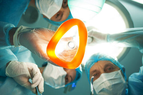 Now try to sleep. Low angle of professional surgeons giving to patient a general anesthetic before an operation. They are holding the equipment and surgical instruments